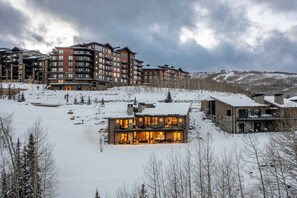 A modern multi-story hotel with a snow-covered landscape, featuring a prominent building with large windows and a well-lit entrance.