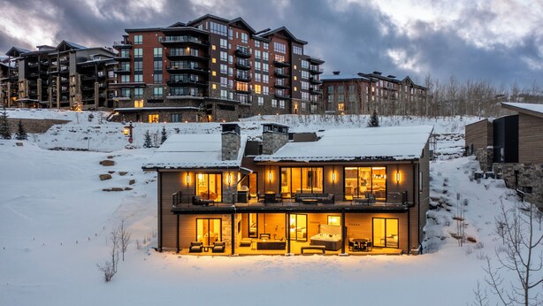 Un immeuble moderne à plusieurs étages, doté de grandes fenêtres et d’un balcon, entouré de neige.