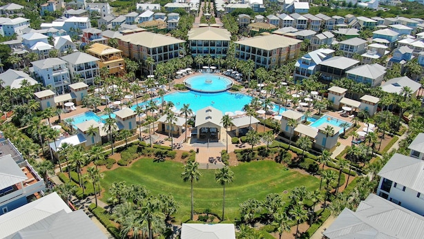An aerial view of a resort with multiple swimming pools, palm trees, and a central building with a large pool. - Seacrest Beach, Lagoon Pool-Front + Free tickets: Dolphin Cruise & More! (Inlet Beach)