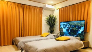A hotel room with two beds, a large TV on the wall, and a potted plant. - Kamei House (Tokyo)