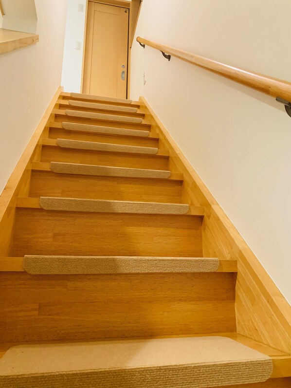 Una escalera de madera con barandilla y una puerta de madera al final.