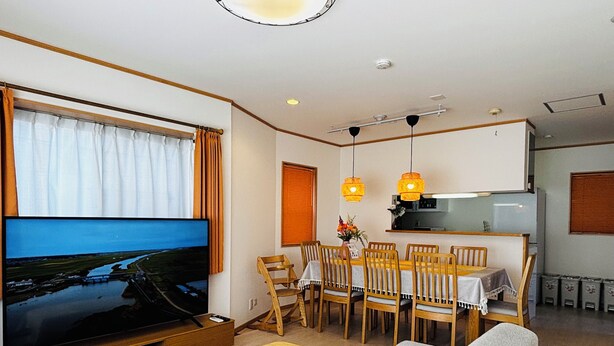 A modern living room with a TV, sofa, dining table, and kitchen area. - Kamei House (Tokyo)