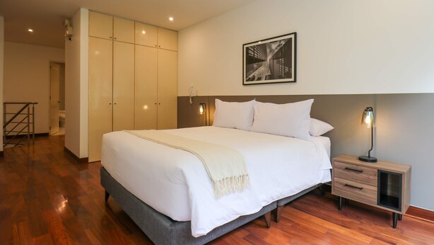 A bedroom with a large bed, a nightstand, a wardrobe, and a framed picture on the wall. - w Graceful 1BR With Balcony in Miraflores (Lima)