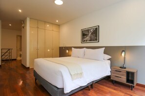 A bedroom with a large bed, a nightstand, a wardrobe, and a framed picture on the wall.