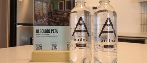 A brochure titled 'DESCUBRE PERÚ' and two bottles labeled 'andea sin gas' on a table.