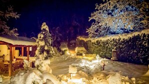 A snow-covered outdoor area with a wooden structure, possibly a restaurant, and snow-covered trees. - Kedra Village Superior Chalet - Mountain Escape (Makrakomi)