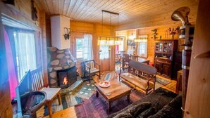 A cozy log cabin interior with a stone fireplace, wooden furniture, and a dining area. - Kedra Village Superior Chalet - Mountain Escape (Makrakomi)