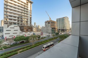 A modern urban street with a bus, high-rise buildings, and construction cranes. - Stayshort - Chic Studio Apartment in JVC Sleeps 4 (Dubai)