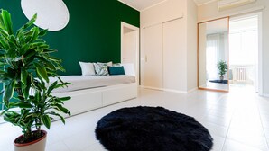 A modern bedroom with a green accent wall, a white sofa, a black furry rug, and a potted plant. - VivimiHome | Cozy Design Flat - San Siro (Milano)
