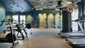 Et fitnesscenter med træningsmaskiner, vægtløftningsområder og spejle.