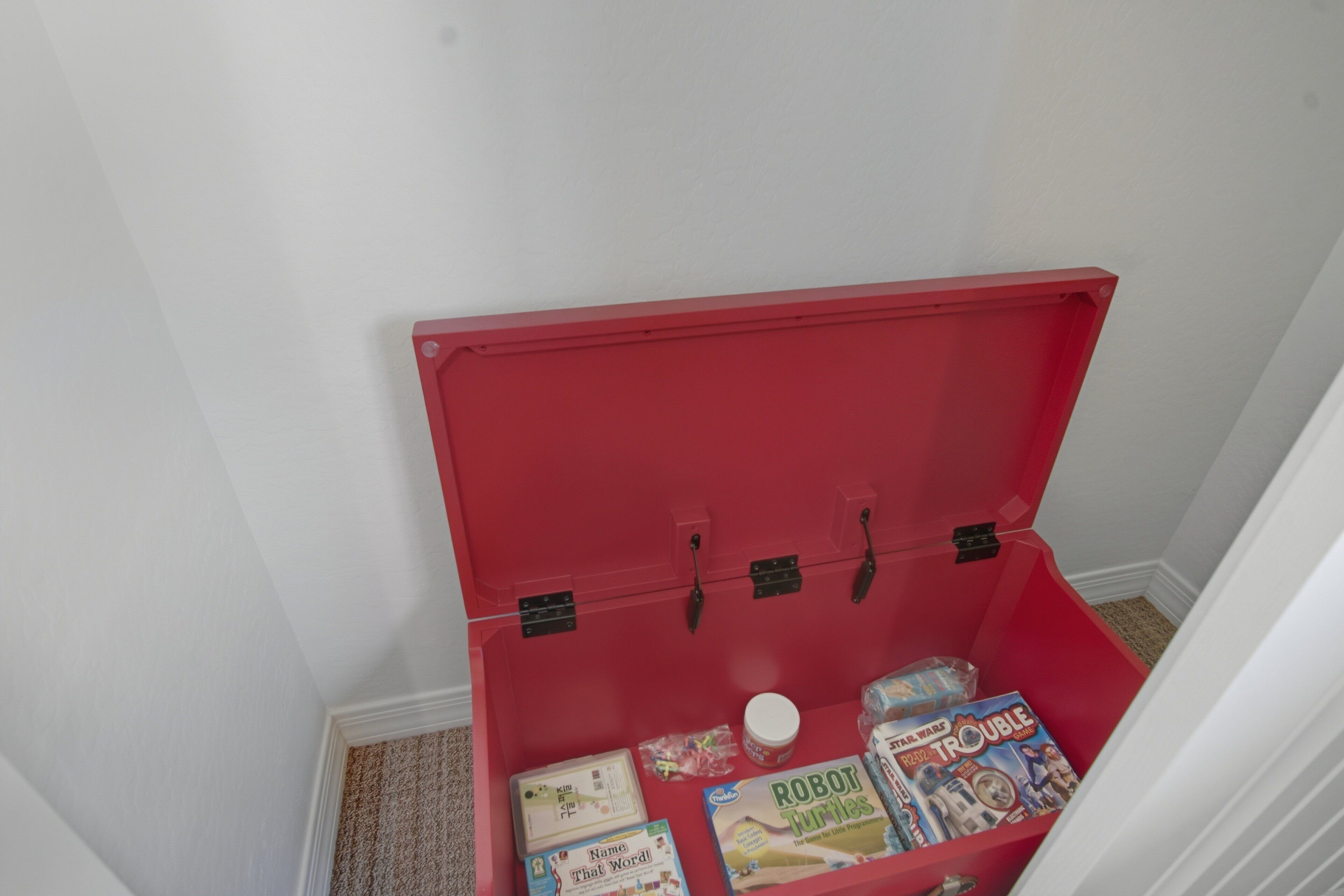 Une boîte de rangement rouge contenant des livres et un bocal.