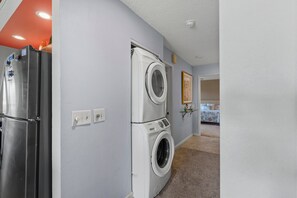 A laundry room with a stainless steel refrigerator, a front-loading washer, and a dryer. - Maui Kamaole, #h-208 2 Bedroom Condo (Kihei)