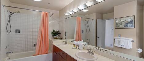 Un baño moderno con bañera, ducha, tocador y un espejo grande.