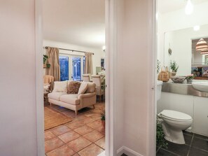 A living room with a sofa, a dining area, and a view through a glass door. - Berkley Cottage (Colchester)