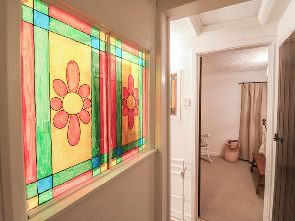 A hallway with a stained glass window featuring colorful flowers. - Berkley Cottage (Colchester)