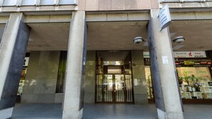 Une entrée d’immeuble avec une porte en verre, de grandes colonnes et une enseigne indiquant un centre d’affaires.