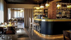 Un espace bar moderne avec un comptoir incurvé, des tabourets de bar et des luminaires suspendus.