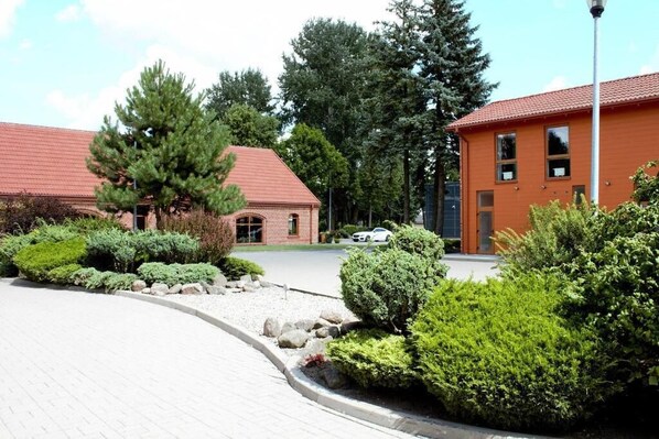 A building with a red roof and brick walls, surrounded by well-maintained landscaping and a paved driveway.