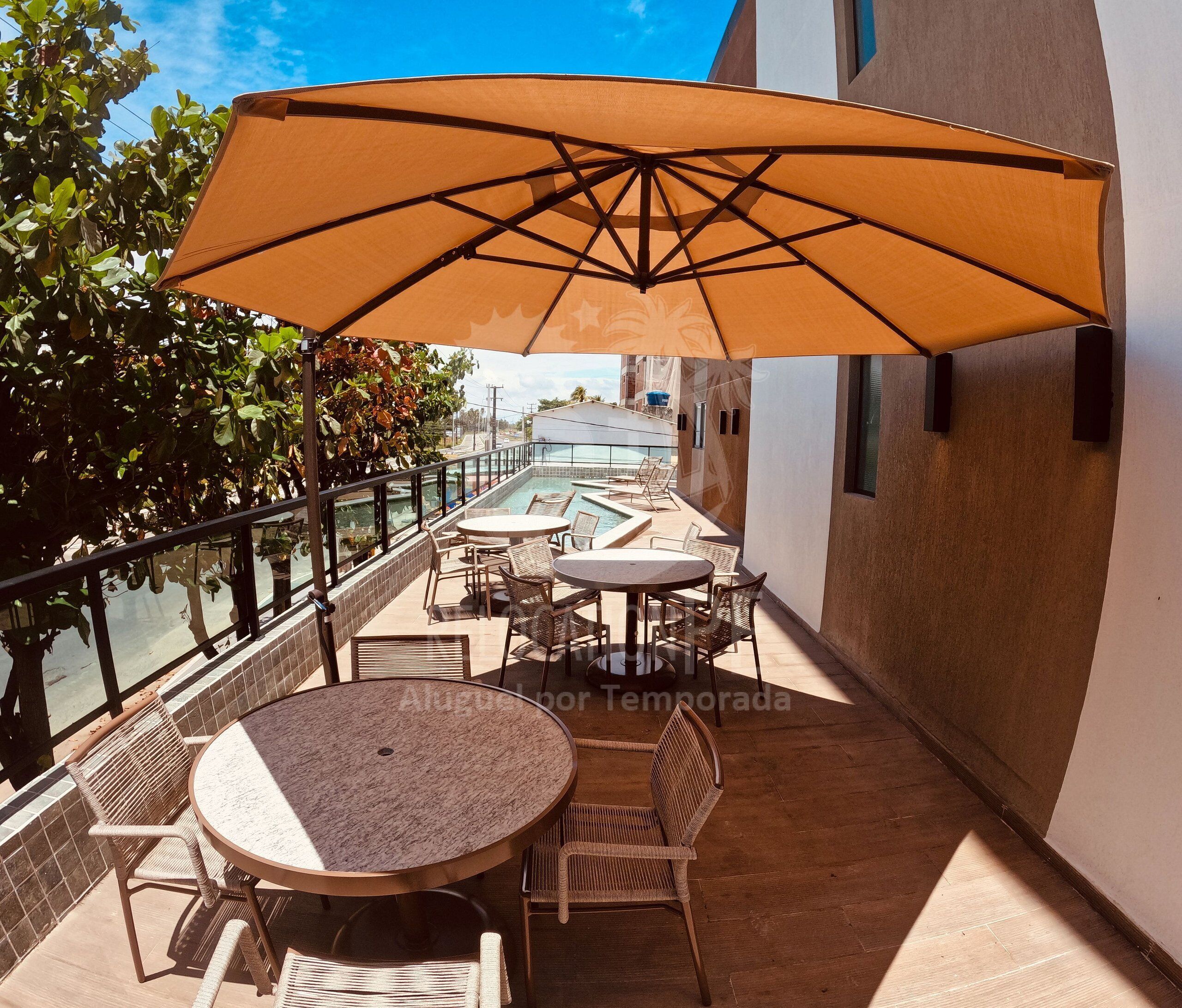 A rooftop terrace with a pool, outdoor seating, and a large umbrella.