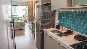 Een moderne keuken met een ingebouwde vaatwasser, een spoelbak met kraan en een raam met uitzicht op een balkon.