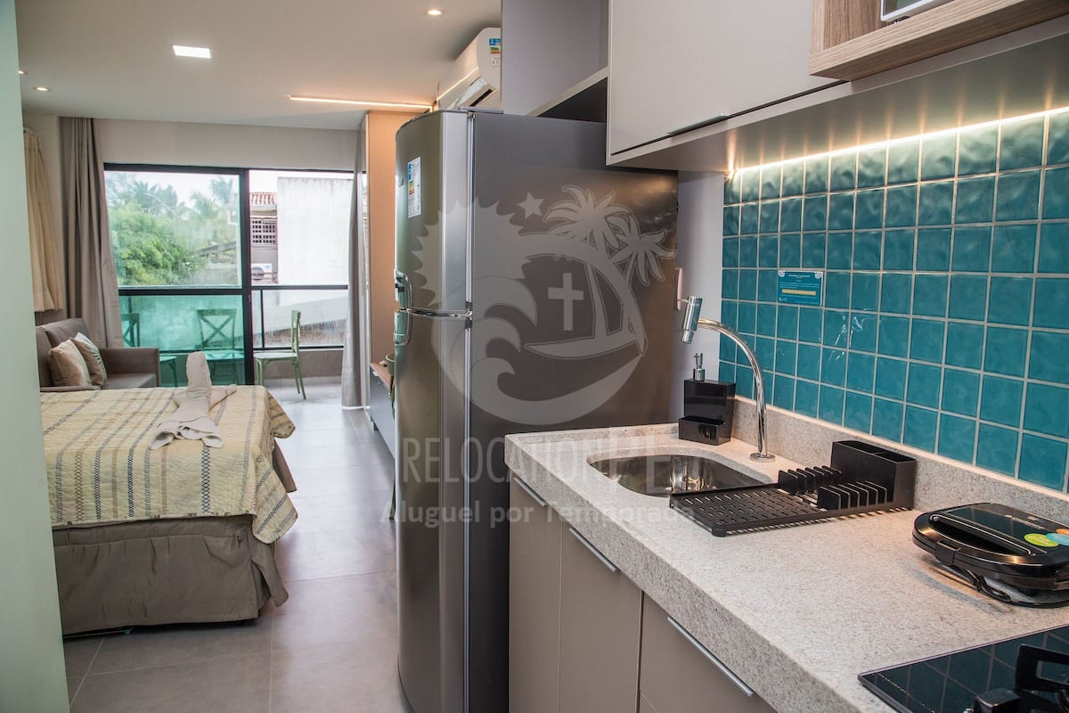 Una cocina compacta con refrigerador, lavamanos y encimera.