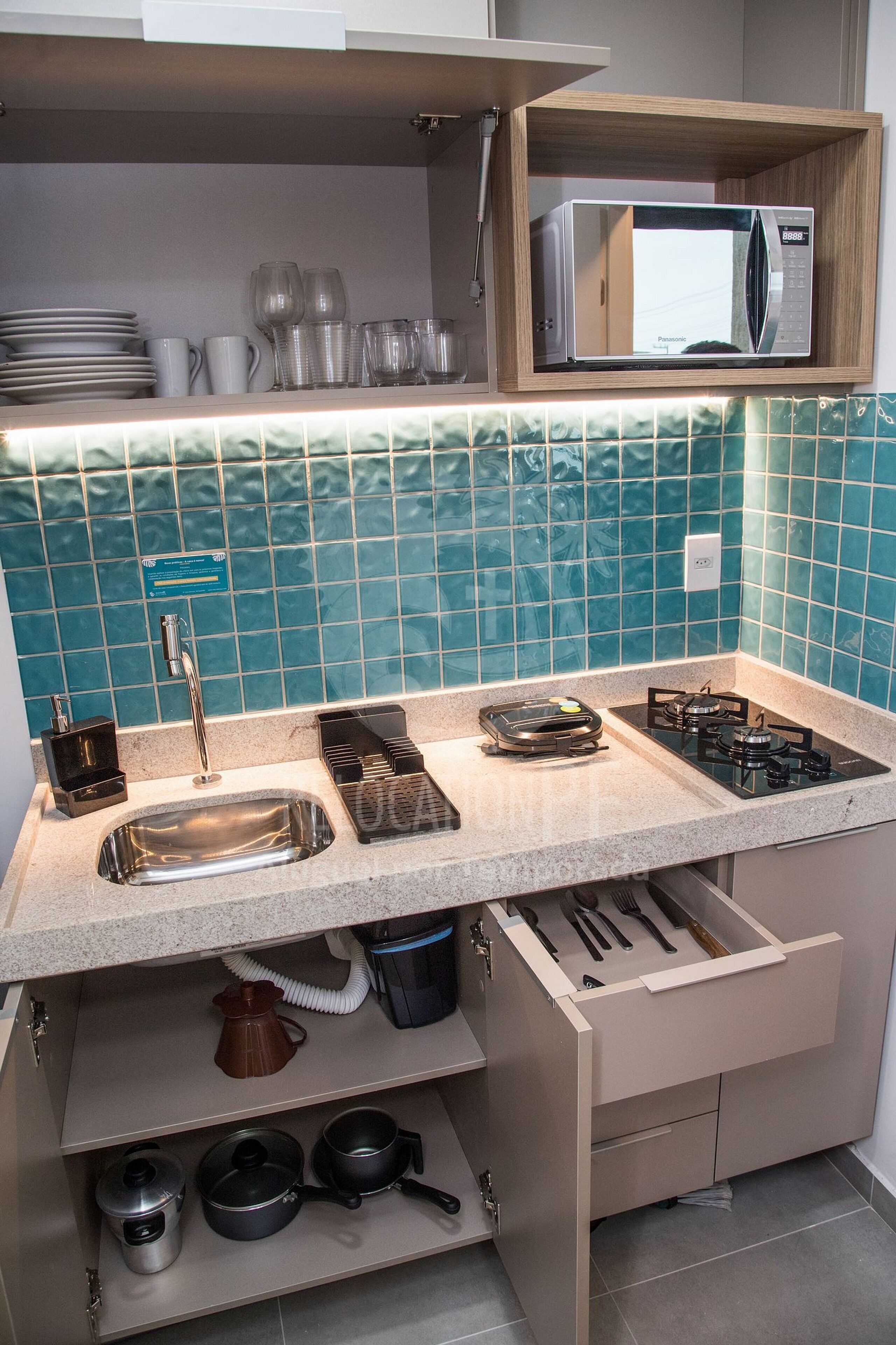 A kitchen with a microwave, sink, stove, and various utensils.