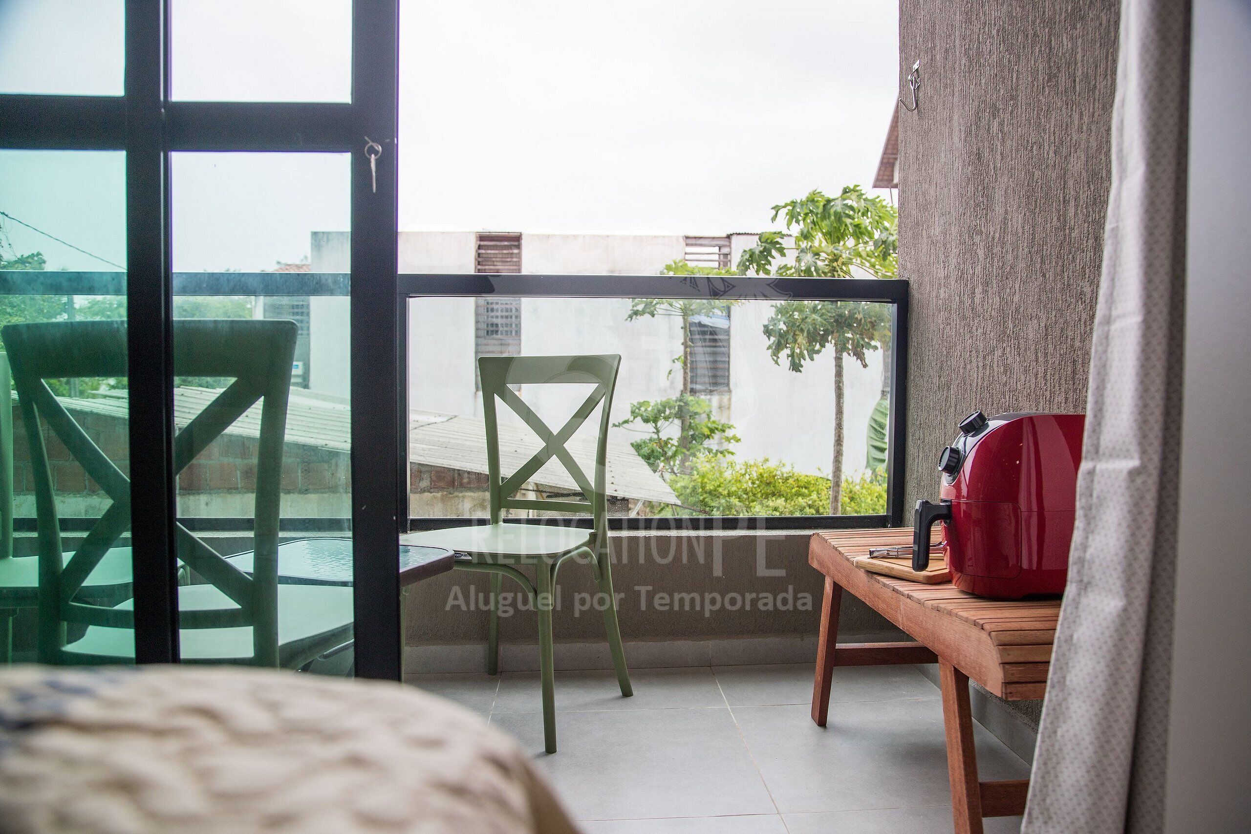A balcony with a chair, a table, and a red suitcase.