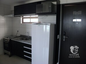 A kitchen with a refrigerator, stove, and sink. - Condomínio Beach Class Conselheiro  (Ipojuca)