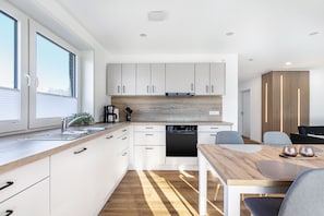 Una cocina moderna con armarios blancos, encimera de madera y lavavajillas integrado.