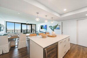 A spacious kitchen with a large island, white cabinetry, and a view to the outside. - Private Balcony With Unforgettable Waterfront Views (Port Aransas)