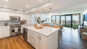 A modern kitchen with white cabinets, stainless steel appliances, and a large island. - Private Balcony With Unforgettable Waterfront Views (Port Aransas)