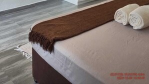 Ein modernes Schlafzimmer mit einem großen Bett, einem Kleiderschrank und einer Pendelleuchte.