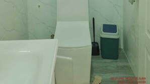Ein Badezimmer mit Toilette, Mülleimer und Badewanne.