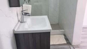 Ein modernes Badezimmer mit integriertem Waschbecken, einer Dusche und einem Spiegel.