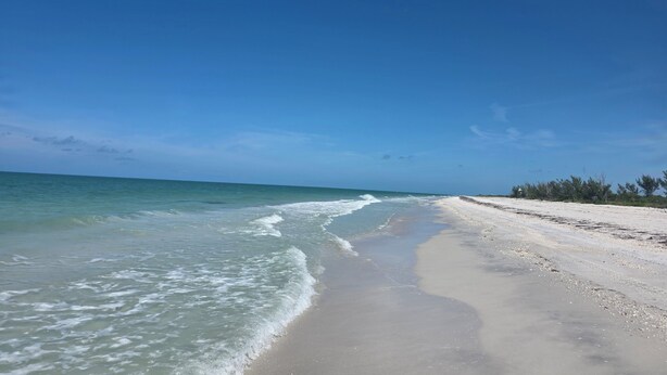 Uma praia com águas azul-claras e areal arenoso.