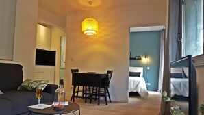 Una sala acogedora con un sofá, una mesa de comedor y una cama al fondo.