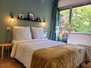 A bedroom with a bed, bedside tables, a window with a view of trees, and wall-mounted lights. - ElFFEL TOWER VIEW - Front Row view + Terrace (Paris)