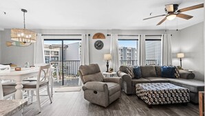 Un salon moderne avec un coin repas, un ventilateur de plafond et une vue sur le paysage urbain.