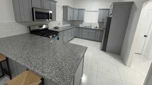 Una cucina con piani di lavoro in granito, elettrodomestici in acciaio inossidabile e mobili in legno grigio chiaro.