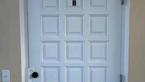 Una porta bianca con una tastiera numerica e un piccolo oblò in alto.
