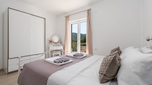 A bedroom with a bed, a bedside table, a mirror, and a view of the outdoors. - Holiday home Silvija by Villas Guide (Primorski Dolac)