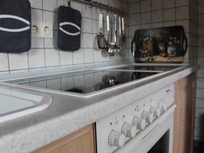 A kitchen with a white countertop, a stove, and a range hood. - Schrichten Apartment on the Edge of the Forest (Schmallenberg)
