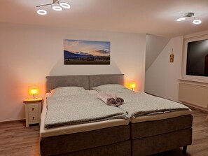 A bedroom with a bed, two bedside lamps, a wall-mounted picture, and a window. - Double Room on the Forest Edge with a View (Schmallenberg)