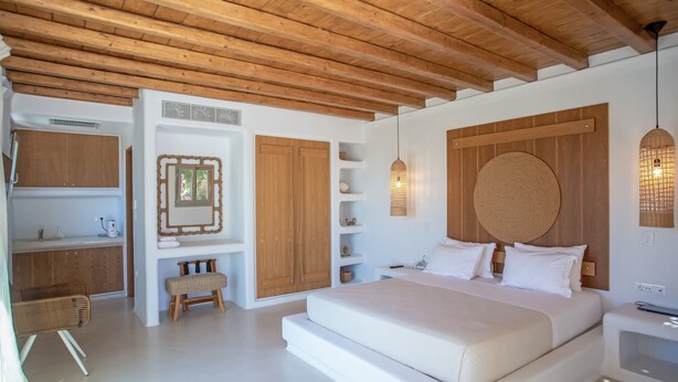 A bedroom with a wooden ceiling, a large bed, a bedside table, a hanging light fixture, and built-in wooden shelves. - Scorpios Dream By Bestofmikonos Country House with Private Pool, Wi-Fi & Air Conditioning (Mykonos)
