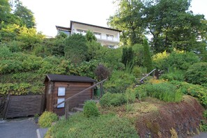 A hillside residential area with a wooden cabin and a two-story building. - Holiday Apartment Eichenwäldchen****, 129 sqm, 3 Bedrooms, Max. 8 Persons (Kirchhundem)