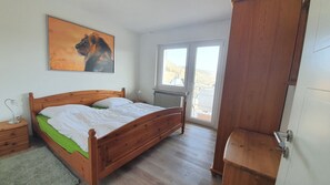 A bedroom with a wooden bed, a radiator, a window, and a door. - Holiday Apartment Eichenwäldchen****, 129 sqm, 3 Bedrooms, Max. 8 Persons (Kirchhundem)