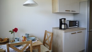 Une cuisine avec des meubles de rangement en bois, un four à micro-ondes, une machine à café et une table à manger avec des chaises.