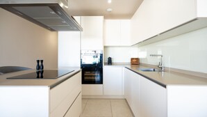 Una cocina moderna con gabinetes blancos, una campana extractora de acero inoxidable y un horno empotrado.