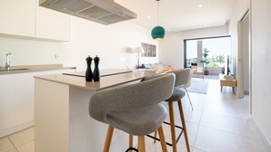 Una cocina moderna con una isla central, taburetes de bar y una lámpara colgante.