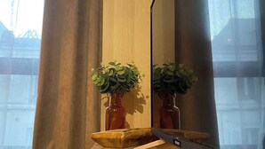 A room with a wooden desk, two potted plants, a mirror, and a view of a bridge through the window. - Le rétro du Marché (La Rochelle)